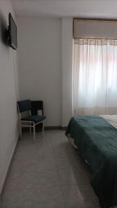 a bedroom with a bed and a chair and a window at Departamento Romalu in Santa Teresita