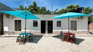 two tables and chairs with umbrellas in front of a building at Cabaña Datalu 2 in Coveñas