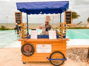 a food cart with a chef standing next to a pool at Dreams Natura Resort & Spa - All Inclusive in Cancún