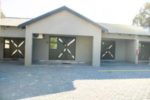 a building with four doors and a brick parking lot at Silver Lake Lodge Rustenburg in Rustenburg