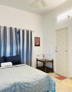 a bedroom with a bed and curtains and a table at Lima Beach House Varkala in Varkala