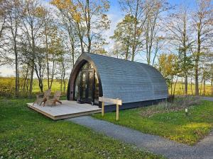 a small cabin with two chairs in the grass at Tiny House De Hagekrûper in Westergeest