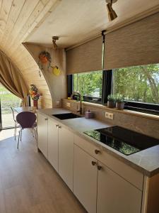 a kitchen with white cabinets and a table and windows at Tiny House De Hagekrûper in Westergeest