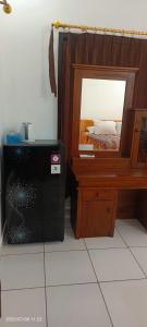 a bedroom with a bed and a mirror next to a microwave at Dewenten Backpacker II in Tulamben