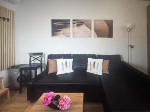 a living room with a black couch and some flowers at Sea waves suite in Hersonissos
