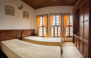 two beds in a room with two windows at Pachilov House in Zlatograd