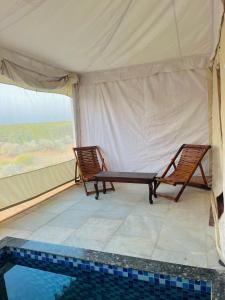 a tent with two chairs and a swimming pool at HP Desert Luxury Camp in Jaisalmer