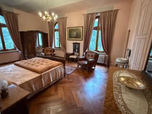 a living room with a bed and chairs and windows at Io&Te La Suite di Villa Monteriolo in Canelli