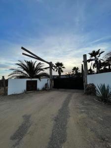 Una puerta en medio de un camino de tierra con palmeras. en DaNik Valle, en Francisco Zarco