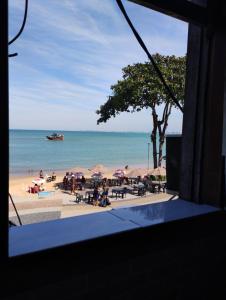 una playa con mesas y sombrillas y un barco en el agua en Pousada Pé na Praia, en Rio das Ostras