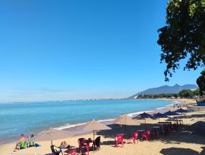 Una playa con sillas y sombrillas y el océano. en Pousada Pé na Praia, en Rio das Ostras