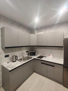 eine Küche mit weißen Schränken und einer Spüle in der Unterkunft New Comfort Apartment in Hostomelʼ