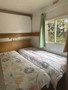 two beds in a small room with a window at Chalet Proche mer in Latour-Bas-Elne
