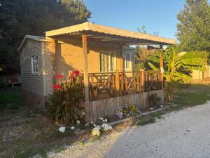 a small cabin with a wooden porch with a deck at Chalet Proche mer in Latour-Bas-Elne