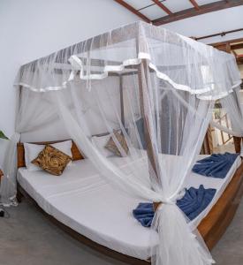 una cama con dosel y mosquiteras blancas. en Stay Salty, en Matara
