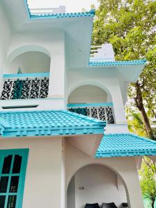a white house with blue balconies and trees at Lima Beach House Varkala in Varkala +18 photos