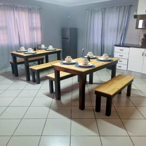 een keuken met drie tafels en een bank erin bij Sunnyridge Sky East London in East London