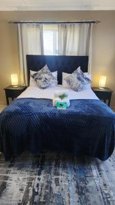 een slaapkamer met een bed met een blauw dekbed en kussens bij Sunnyridge Sky East London in East London +10 foto's