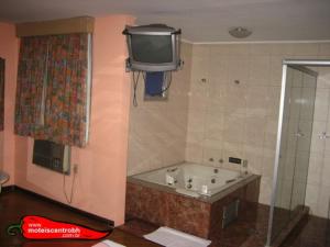 baño con bañera y TV en la pared en Signus 2, en Belo Horizonte