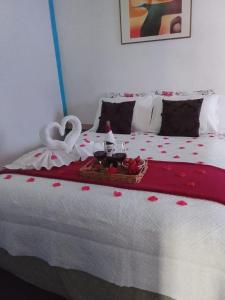 カンポス・ド・ジョルドンにあるKitnet Privativa no Portal de Campos do Jordãoの2羽の白鳥と餌の載ったトレイが置かれたベッド