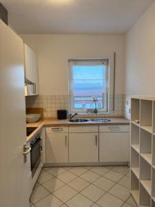 a white kitchen with a sink and a window at Schöne Wohnung mit Aussicht in Oettingen in Bayern +7 photos