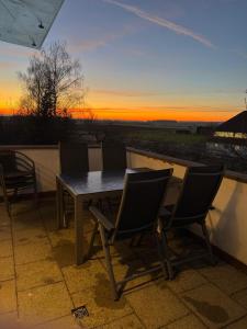 a table and chairs on a balcony with a sunset at Schöne Wohnung mit Aussicht in Oettingen in Bayern
