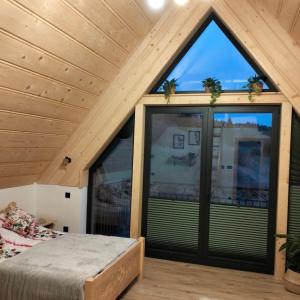 a bedroom with a large window in a house at Siedem Światów Domek in Jurgów