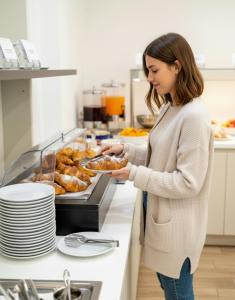 a woman in a kitchen holding a plate of food at Hotel Giotto in Padova
