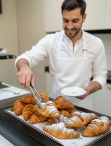 a man in a kitchen preparing croissants on a tray at Hotel Giotto in Padova