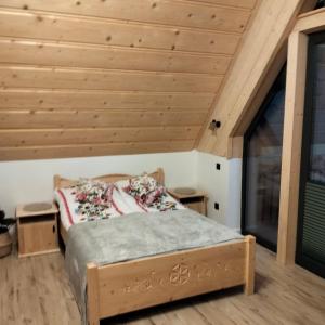 a bed in a room with a wooden ceiling at Siedem Światów Domek in Jurgów
