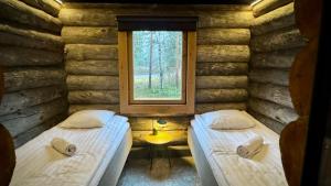 twee bedden in een blokhut met een raam bij Kelokurki - The Luxury Lodge Where Serenity Meets the Northern Lights in Levi