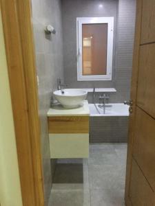 a bathroom with a sink and a mirror and a tub at Appartement Les Rosiers in Hammam Sousse