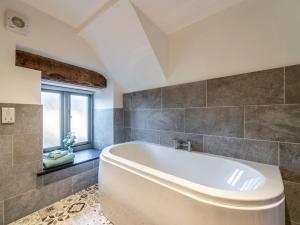 a large white tub in a bathroom with a window at 4 Bed in Denbigh 62947 in Llannefydd