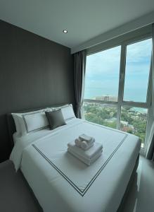 ein Schlafzimmer mit einem großen weißen Bett mit einem großen Fenster in der Unterkunft Sky residences - Plage de Pattaya Pratamnak Moderne in Pattaya South