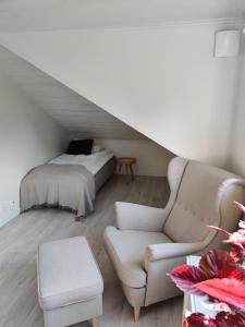 ein Dachzimmer mit einem Bett, einer Couch und einem Sessel in der Unterkunft Gamla Hjälmarvägen 10 in Örebro + 8 Fotos