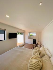 a bedroom with a large bed and a living room at The Coconut Hut Papamoa Beach in Tauranga