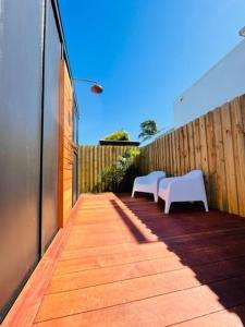 two white chairs sitting on a wooden walkway at The Coconut Hut Papamoa Beach in Tauranga