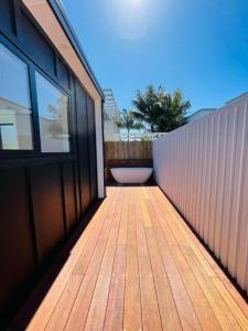 a balcony with a wooden floor and a fence at The Coconut Hut Papamoa Beach in Tauranga