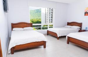 two beds in a room with a window at Sanha Plus Hotel in Santa Marta