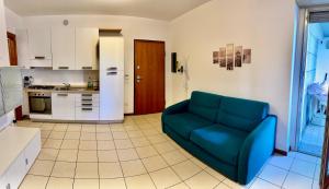 Una sala de estar con un sofá azul y una cocina. en Central apartaments, en Bérgamo