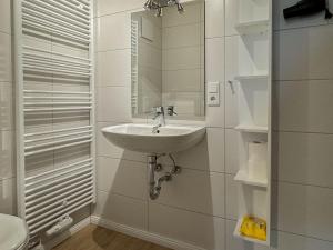 a white bathroom with a sink and a mirror at Kaffeehaus - Fewo 3 in Norderney