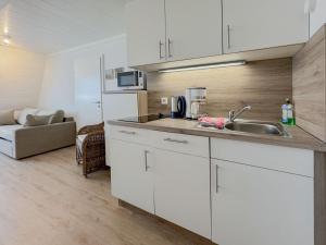 a kitchen with white cabinets and a sink and a couch at Kaffeehaus - Fewo 3 in Norderney