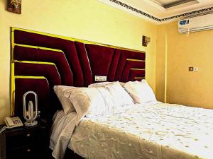 a bedroom with a large bed with a red headboard at Applegate Hotel in Yaoundé +11 photos