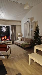 a living room with a christmas tree and a fireplace at Villa Jokiranta in Lapland in Ranua