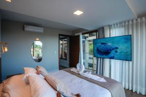 a bedroom with a bed with a tv on the wall at Casa Oceano-Praia do Forte, Cond com Acesso à Praia, Piscina Aquecida in Praia do Forte