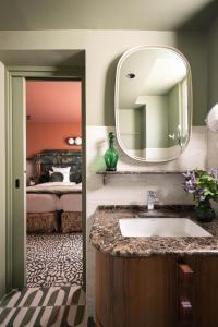 een badkamer met een wastafel en een spiegel en een bed bij 1.75 Paris La Trêve in Parijs