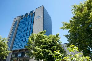 a tall building with trees in front of it at Novotel Sarajevo Bristol in Sarajevo