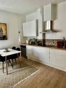 アギラスにあるAguilas Home Beach by Joanの白いキャビネットとテーブルと椅子のあるキッチン