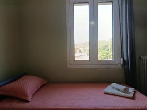 a bedroom with a bed with a window and a towel at Όμορφο φυσικό περιβάλλον in Filippiada