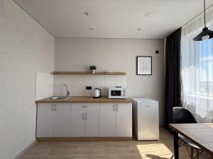 a kitchen with white cabinets and a sink and a microwave at Поділля in Netishyn +10 photos